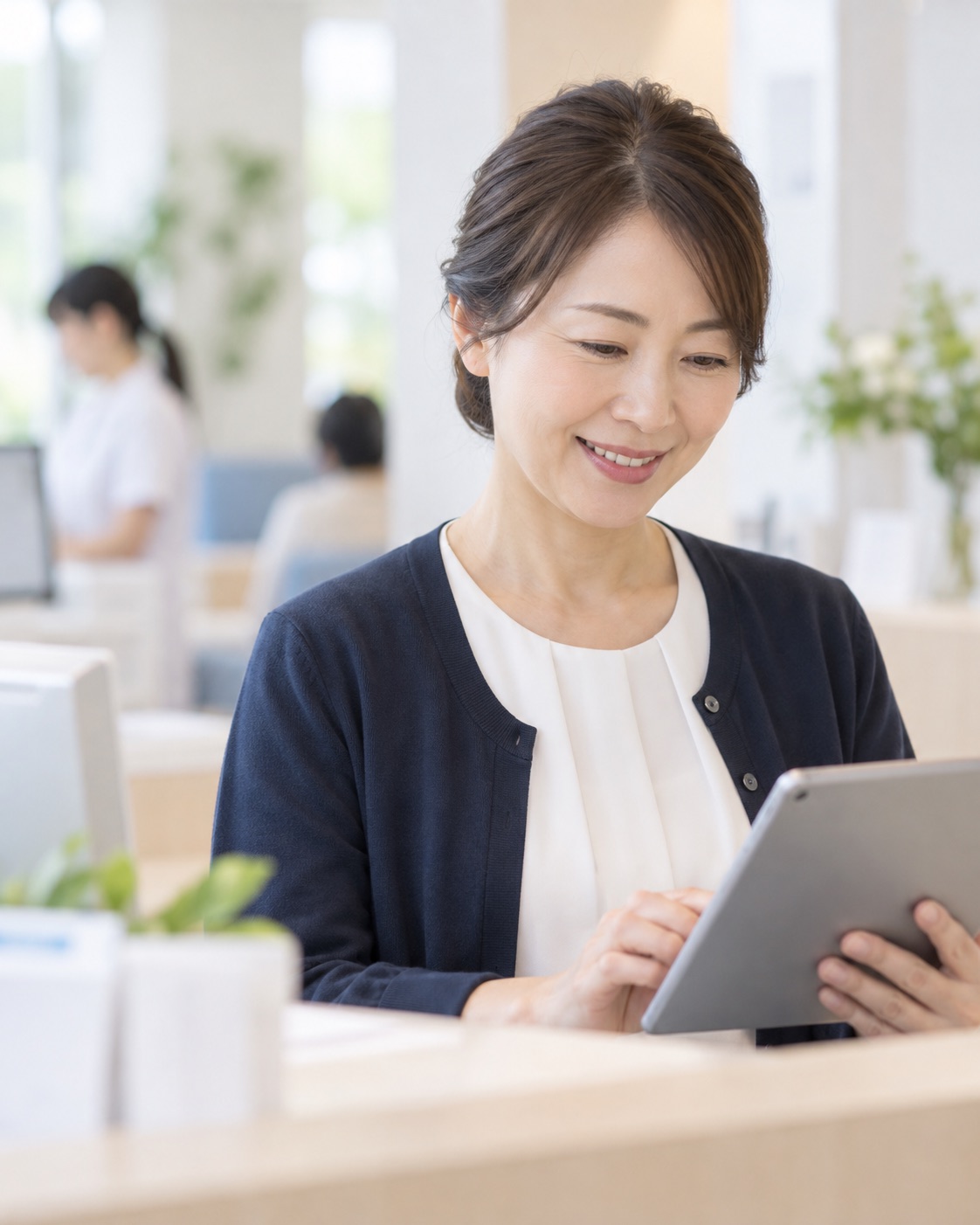 診療所の受付でタブレットの予約を確認するスタッフ